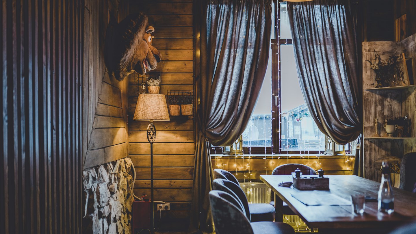 Przytulna jadalnia restauracji z ciepłymi drewnianymi ścianami i zachęcającym oświetleniem.